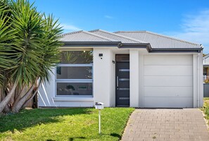 A modern house with a garage, a large window, and a well-maintained lawn. - Reef Retreat Modern Beach HouseSanctuary (Port Noarlunga)