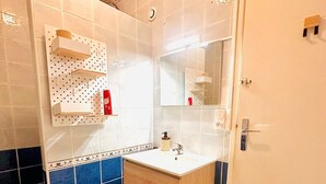 Un bagno con un mobile bagno in legno, uno specchio e un pavimento piastrellato.