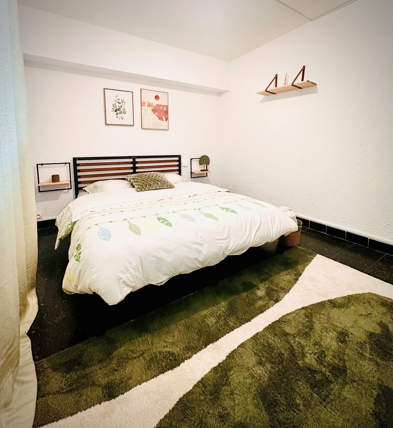 Ein ordentlich eingerichtetes Schlafzimmer mit einem Bett, einem kleinen Nachttisch und einem an der Wand befestigten Regal.