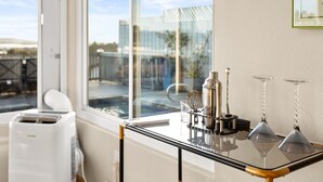 Una cocina moderna con un tostador integrado, una mesa de vidrio con estructura metálica y vistas a la ciudad a través de amplios ventanales.