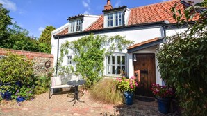 A white house with a red-tiled roof, a wooden door, and a brick wall. - 2 Bed in Stiffkey (oc-1892) (Stiffkey)