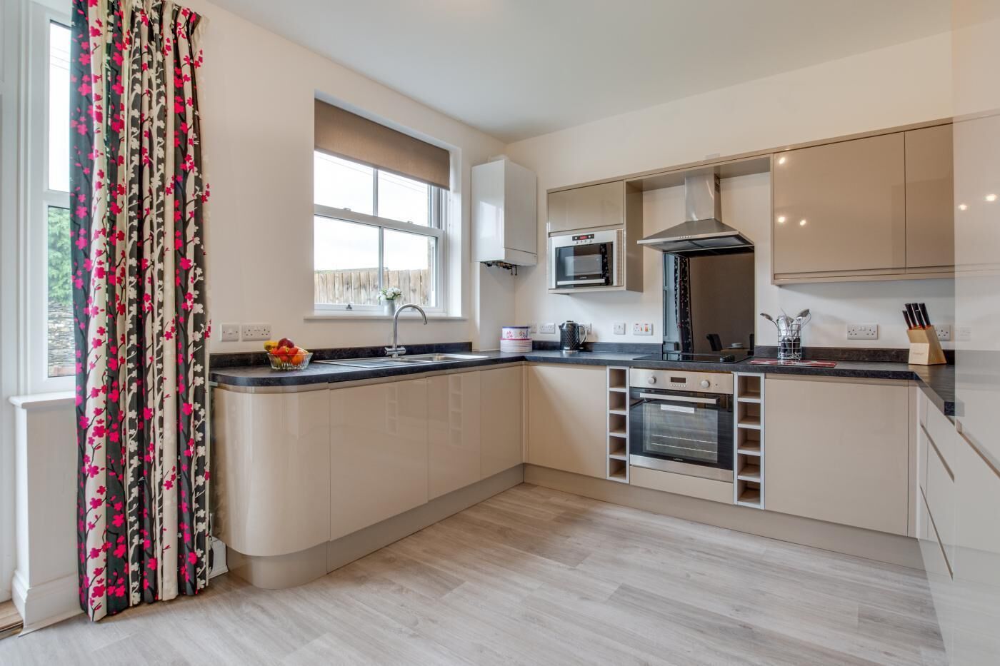A modern kitchen with a built-in oven, microwave, and stainless steel range hood.