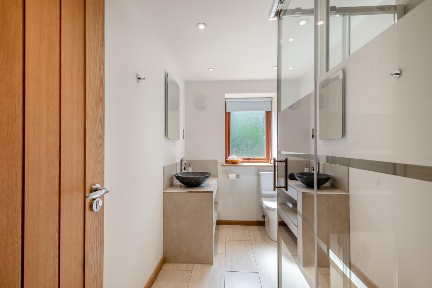 Une salle de bain moderne avec une porte en bois, une fenêtre et une cloison en verre.