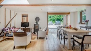 A modern interior with a dining area, seating, a fireplace, and a view of parked cars outside.