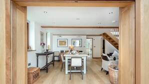 A spacious dining area with a high ceiling, wooden beams, and a staircase leading to an upper level.