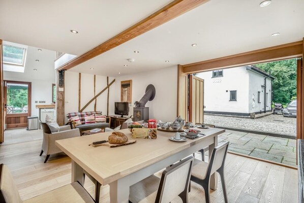 A spacious living area with a dining table set for tea, a fireplace, and a view of the outside.