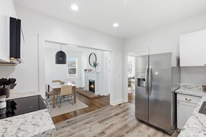 A modern kitchen with a built-in stove, stainless steel refrigerator, and a dining area with a fireplace.
