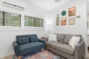 A living room with two sofas, a patterned rug, and wall-mounted artwork.