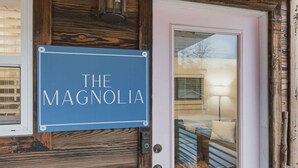 A sign reading "THE MAGNOLIA" mounted on a wooden door. - Cute Cabin, 2 Queens W Shared Hot Tub + Sauna (Easley)