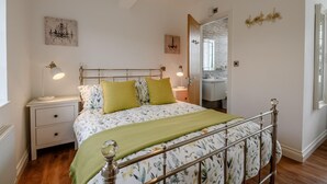 Une chambre à coucher avec un lit, des tables de chevet, une commode, un miroir et une fenêtre.