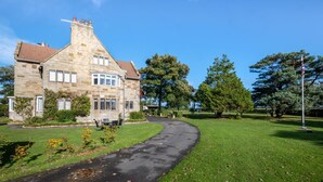 A stone building with a curved driveway leading to a grassy area with trees. - 1 Bed in Hinderwell (oc-wa068) (Port Mulgrave)