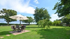 A patio with a table and chairs under a canopy, surrounded by a grassy lawn and trees. - 1 Bed in Hinderwell (oc-wa068) (Port Mulgrave)