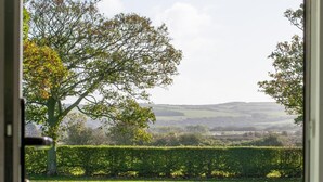 A view through a door of a grassy field with a hedge and trees in the background. - 1 Bed in Hinderwell (oc-wa068) (Port Mulgrave)
