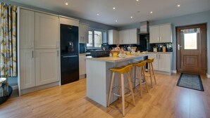 A modern kitchen with a central island, bar stools, and a built-in oven. - 3 Bed in Coelbren (oc-way238) (Coelbren)