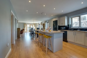 Una cocina moderna con una isla central, taburetes de bar y una zona de comedor con sillas.