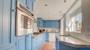 Una cocina con gabinetes azules, un horno de acero inoxidable, una encimera de granito y un salpicadero de azulejos.