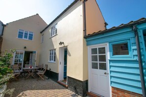 A two-story house with a patio area, a door, and a window. - 3 Bed in Southwold (oc-sdco) (Southwold)