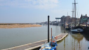 Ein Yachthafen mit vertäuten Booten, einer Holzsteganlage und Gebäuden im Hintergrund.