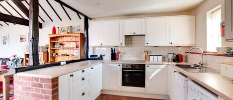 Een microgolfoven, een oven, een vaatwasser, kookgerei, borden en bestek