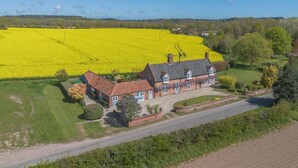Ein zweistöckiges Haus mit Garten und einem Feld gelber Blumen im Hintergrund.