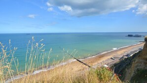 A coastal view with a sandy beach, a fishing net, and a pier in the distance. - 3 Bed in Cromer (oc-1909) (Cromer)