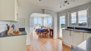 A modern kitchen with a dining area, large windows, and a view of the sea. - 3 Bed in Cromer (oc-1909) (Cromer)
