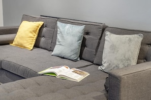 A grey sofa with three cushions in different colors and a book on it. - 3 Bed in Cardiff (oc-bow65) (Cardiff)