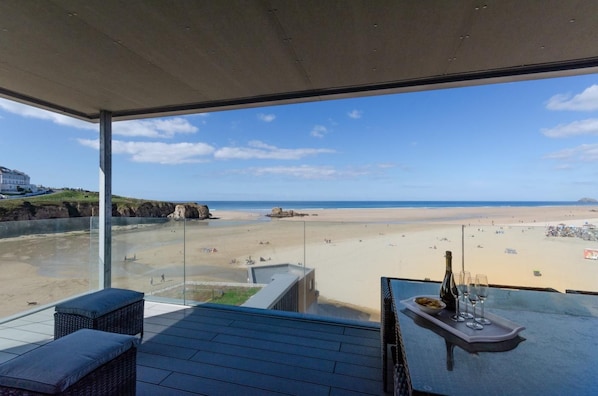 A balcony with a view of a beach and the sea.