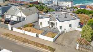 Ein Küstenwohngebiet mit einem weißen Gebäude, das ein flaches Dach und einen kleinen Garten hat.