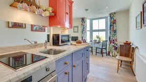 Una cocina moderna con un armario rojo, un microondas y una zona de comedor con mesa y sillas.