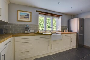 A kitchen with a built-in sink, a coffee maker, and a refrigerator. - 3 Bed in North Creake (oc-1916) (North Creake)