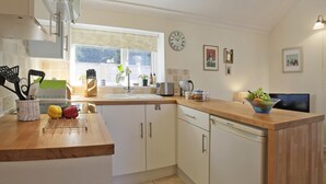Een moderne keuken met witte kasten, een houten aanrecht, een spoelbak en een raam.