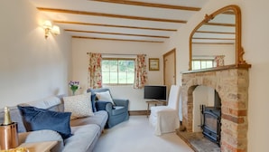 A cozy living room with a sofa, a television, a fireplace, and a window with floral curtains. - 3 Bed in Crayke (oc-y056) (Crayke)