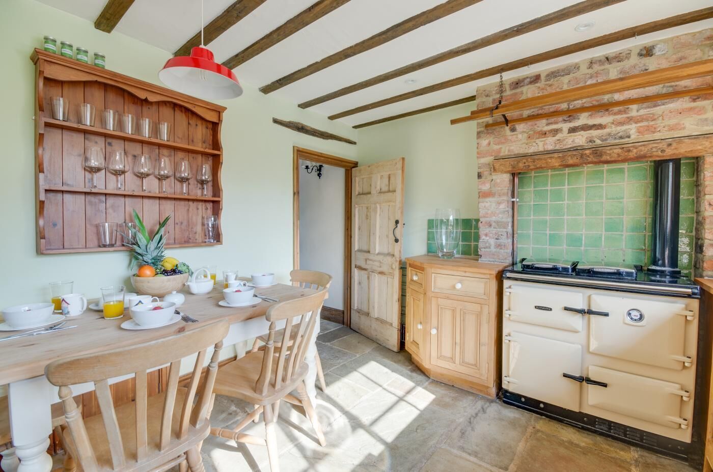 A rustic kitchen with wooden furniture, a brick wall, and a vintage stove.