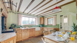 A kitchen with wooden cabinets, a stone countertop, and a dining area with a table set for breakfast. - 3 Bed in Crayke (oc-y056) (Crayke)