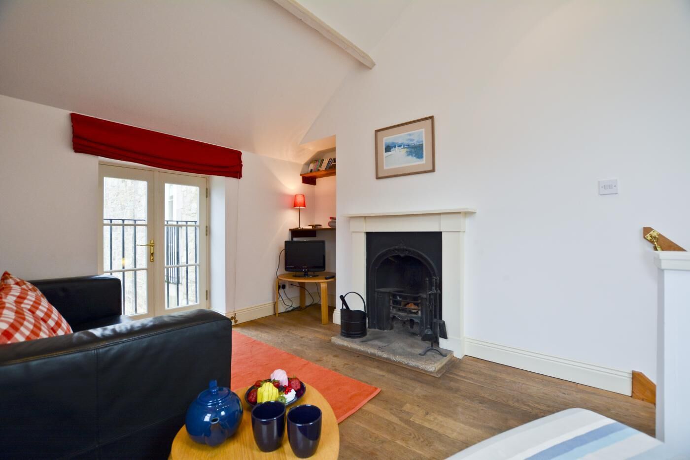 Una sala de estar con chimenea, televisor y una cortina roja.