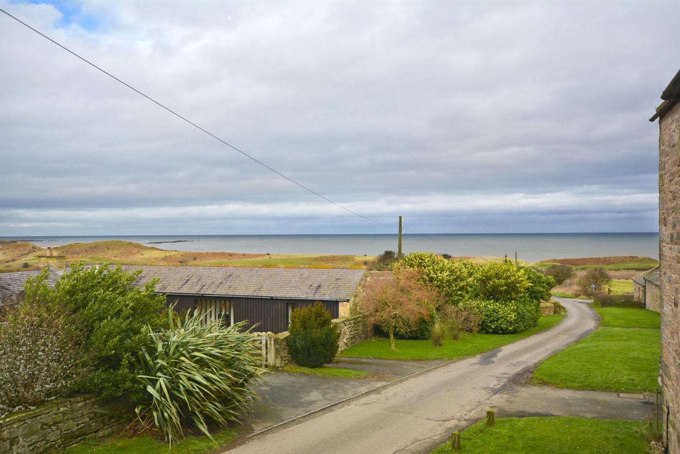 A rural road leading to a stone house with a view of the sea.