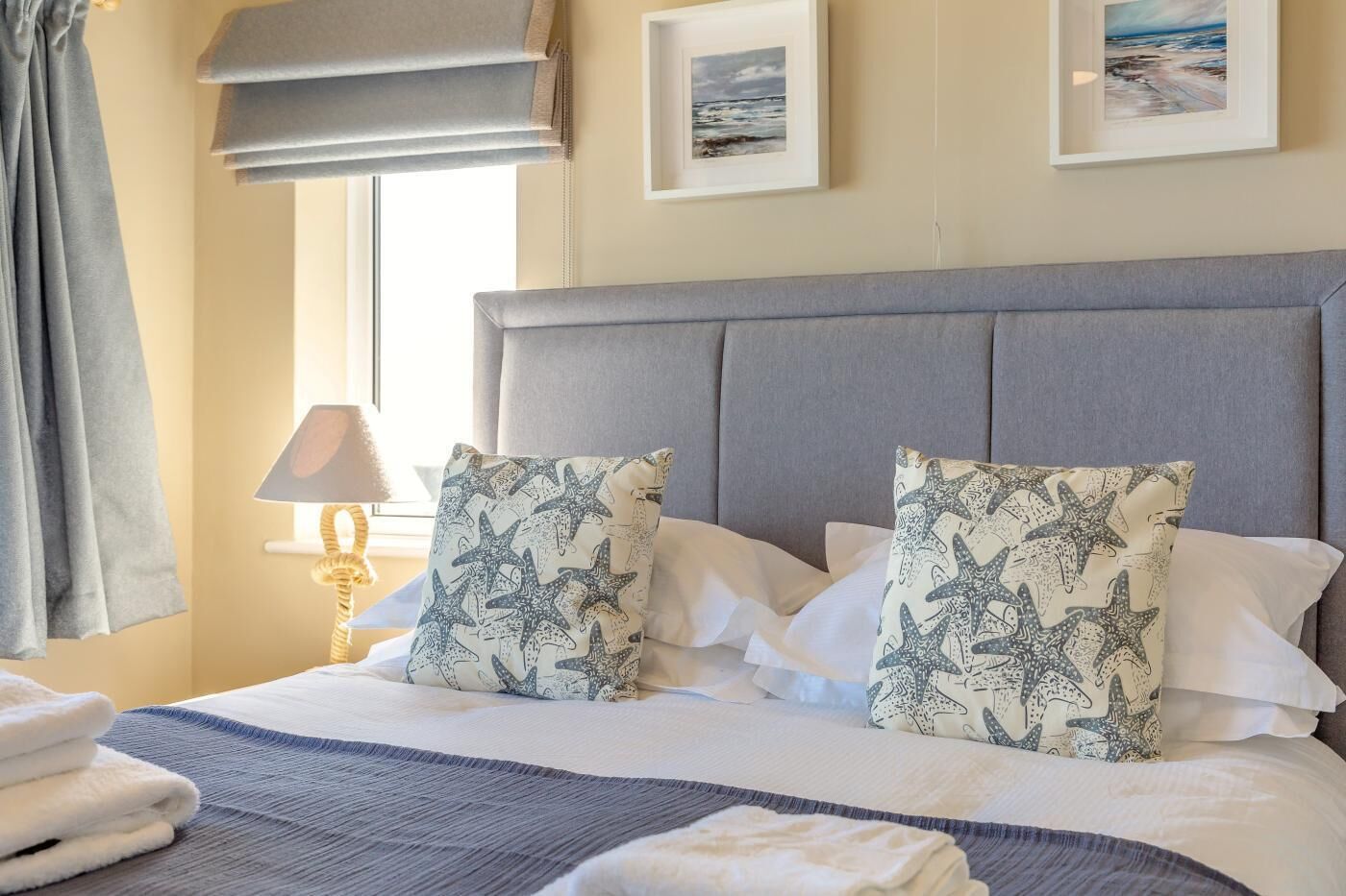 A neatly made bed with patterned pillows, a bedside lamp, and a framed picture on the wall.