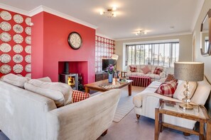 A living room with a fireplace, a sofa set, a coffee table, and a television. - 5 Bed in Seahouses (oc-nb621) (Seahouses)