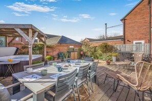 Un patio con una mesa y sillas, un jacuzzi y una casa de ladrillo al fondo.