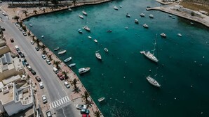 A coastal town with a marina filled with boats, a road parallel to the water, and buildings along the shore. - Soft Coastal Vibes with King Beds & Balcony! (St. Paul`s Bay)