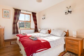 A bedroom with a bed, bedside tables, a window with curtains, a wall-mounted light fixture, and a radiator. - 2 Bed in Chatton (oc-nb620) (Chatton)