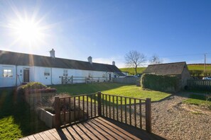 A white cottage with a wooden deck, a fenced yard, and a clear sky. - 2 Bed in Chatton (oc-nb620) (Chatton)