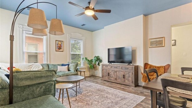 A spacious living room with a green sofa, a coffee table, a TV, and a ceiling fan. - Historic south park gem - close to UD, MVH & more. (Dayton)