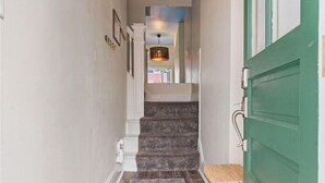 A hallway with a green door, white walls, and a carpeted staircase leading to a room. - Historic south park gem - close to UD, MVH & more. (Dayton)