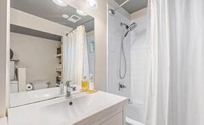 A modern bathroom with a white sink, mirror, and shower.