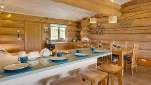 A log cabin-style kitchen with a central island, wooden chairs, and a dining table set for four. - 4 Bed in Alston (oc-nb575) (Alston Moor)