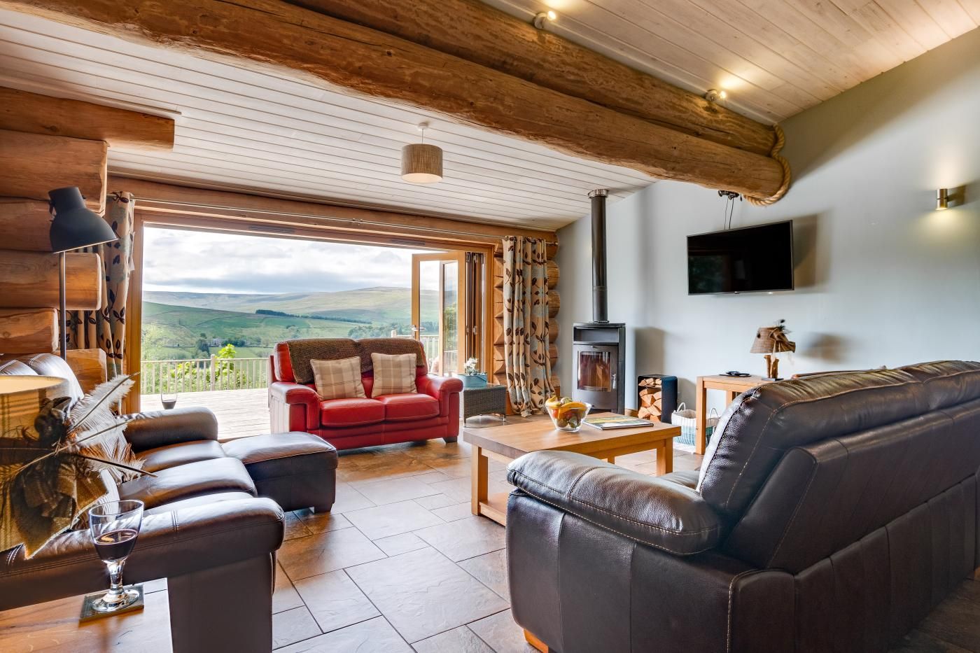 A cozy living room with a fireplace, leather sofas, and a large window offering a scenic view.