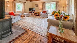 A cozy living room with a fireplace, sofas, a TV, and a large window with curtains. - 2 Bed in Wooler (oc-nb396) (Kirknewton)