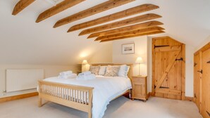 A bedroom with a wooden bed, a nightstand, a radiator, and a wooden door. - 2 Bed in Wooler (oc-nb396) (Kirknewton)